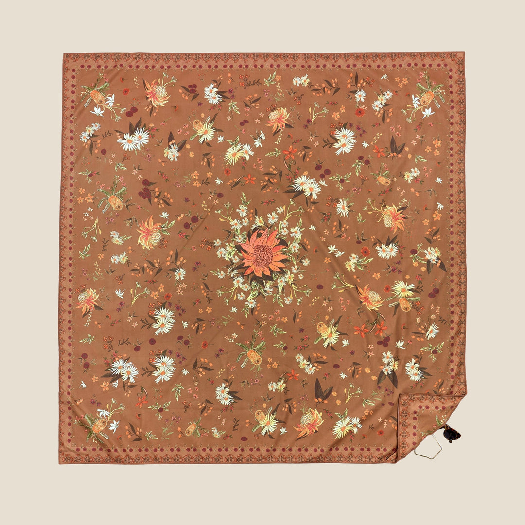 SomerSide Native Ritual XL 160 × 160 cm quick-dry beach towel laid flat, with rust-brown background and cream, orange and green native floral design