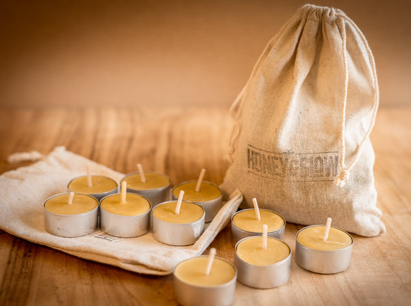 Honey and Glow beeswax tealight candles with aluminium cups beside branded bag
