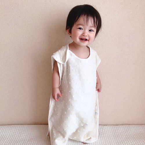 Baby standing wearing the Kontex Natural Dots sleeper in Ivory
