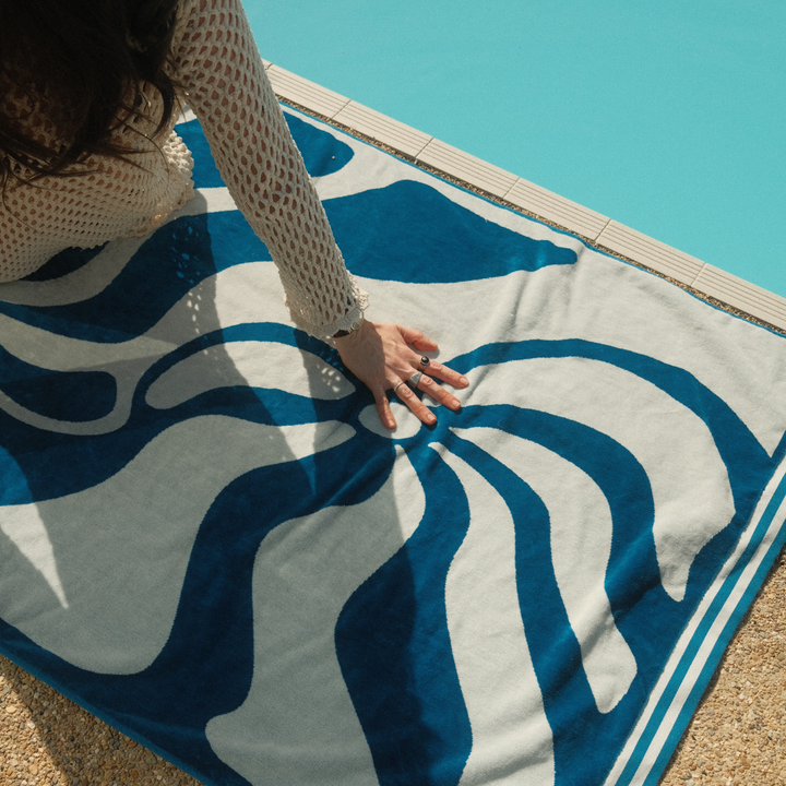 Close view of SomerSide Drift blue and white jacquard cotton beach towel beside a pool