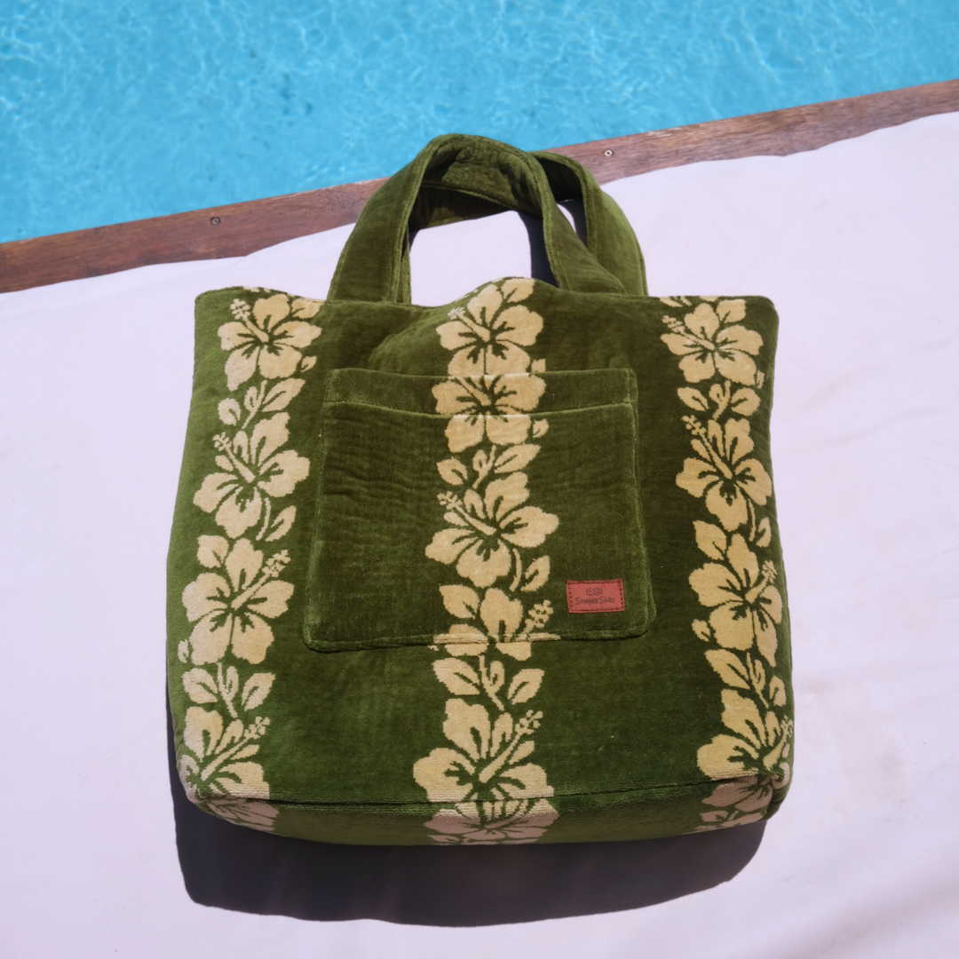 SomerSide Paradiso towelling beach bag, front tote view with cream hibiscus motifs beside a pool